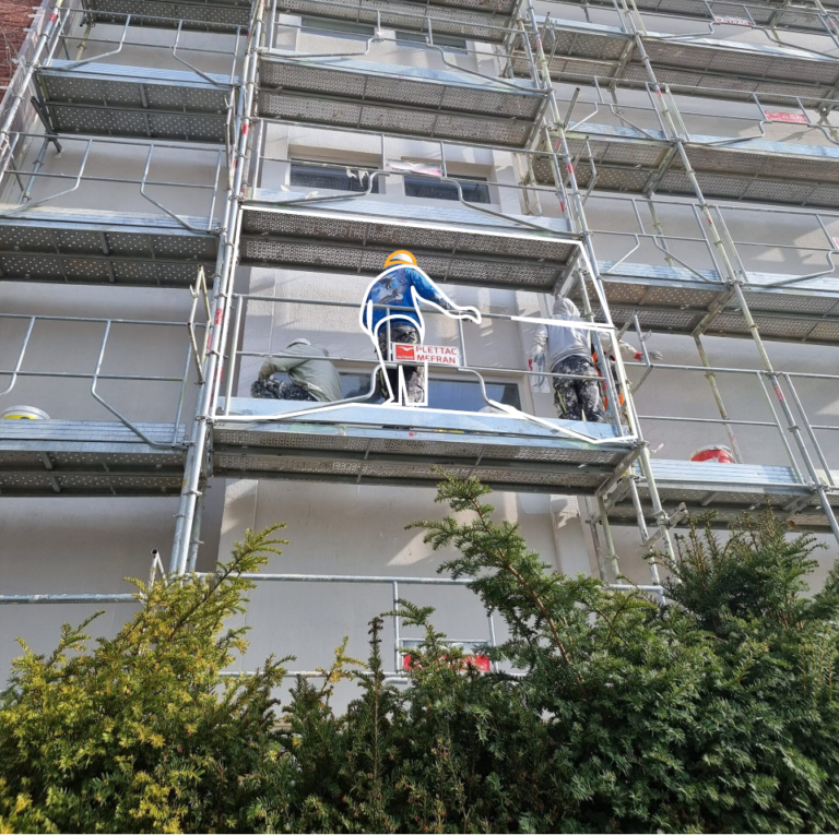 Ouvrier intervenant sur la façade d’un immeuble échafaudé lors de travaux de rénovation