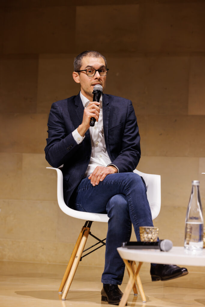 Intervenant assis prenant la parole au Sommet de la Transformation à Paris, en novembre 2025