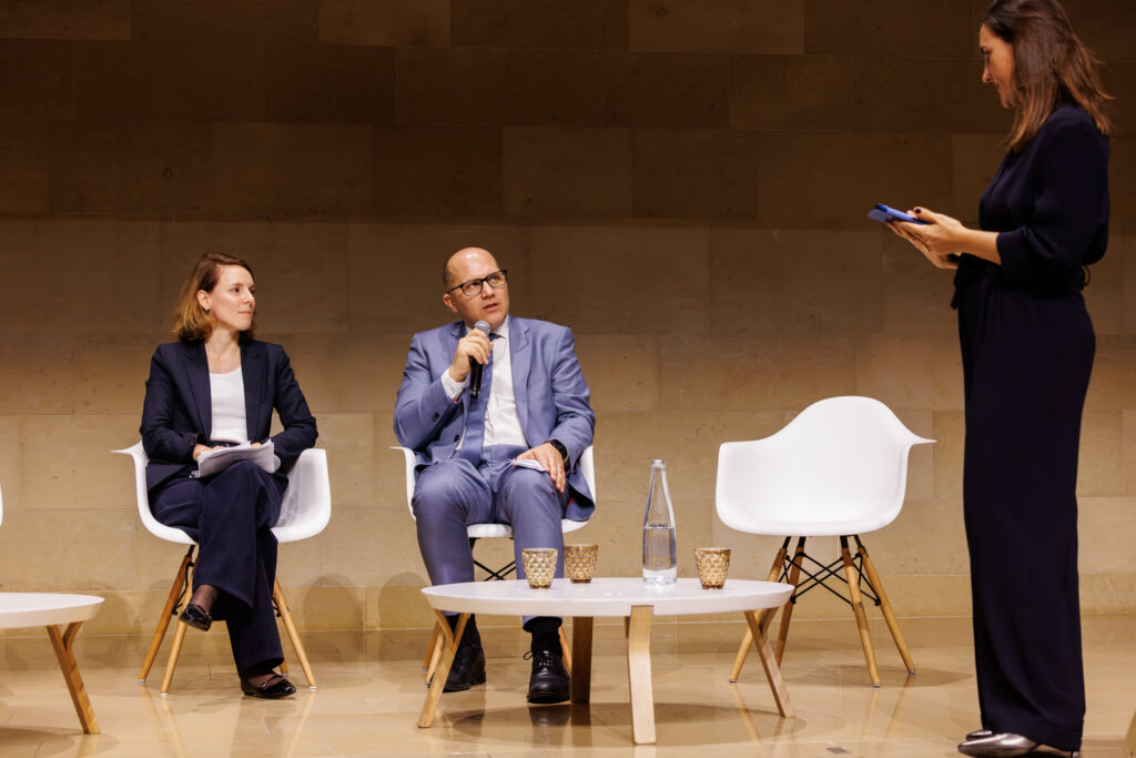 Deux intervenants et une animatrice lors du Sommet de la Transformation à Paris, en novembre 2025