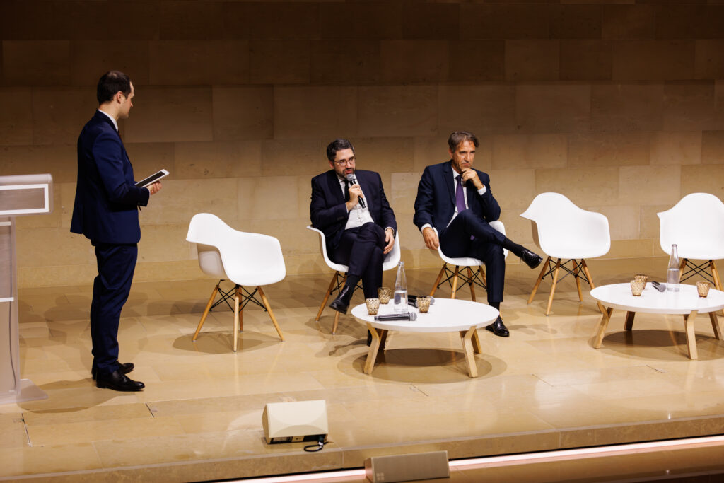 Un animateur et deux intervenants sur scène au Sommet de la Transformation à Paris, en novembre 2025