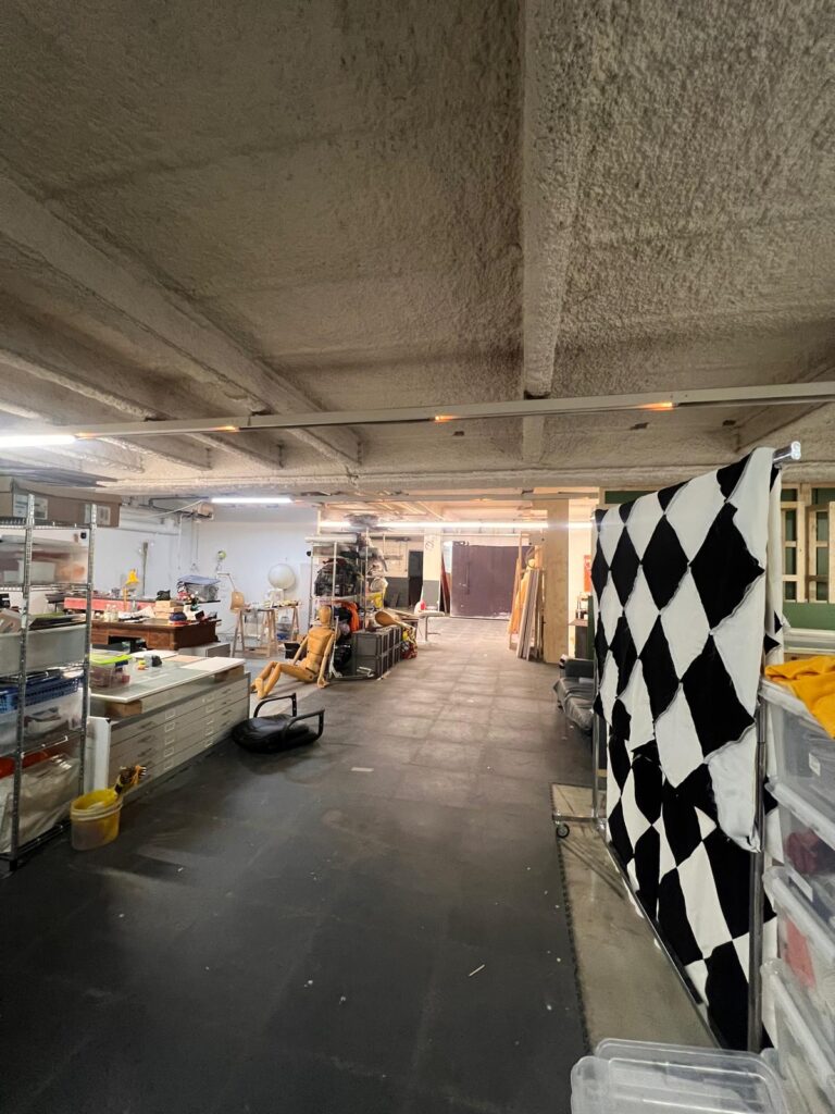 Espace intérieur aménagé sous une dalle en béton, avec rangements et rideau à damier, le 3 février 2026