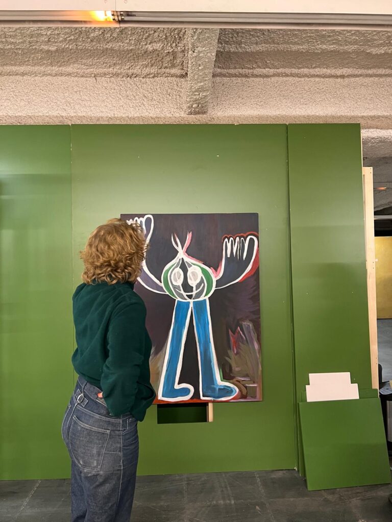 Personne observant une peinture colorée exposée sur un mur vert à République, le 3 février 2026